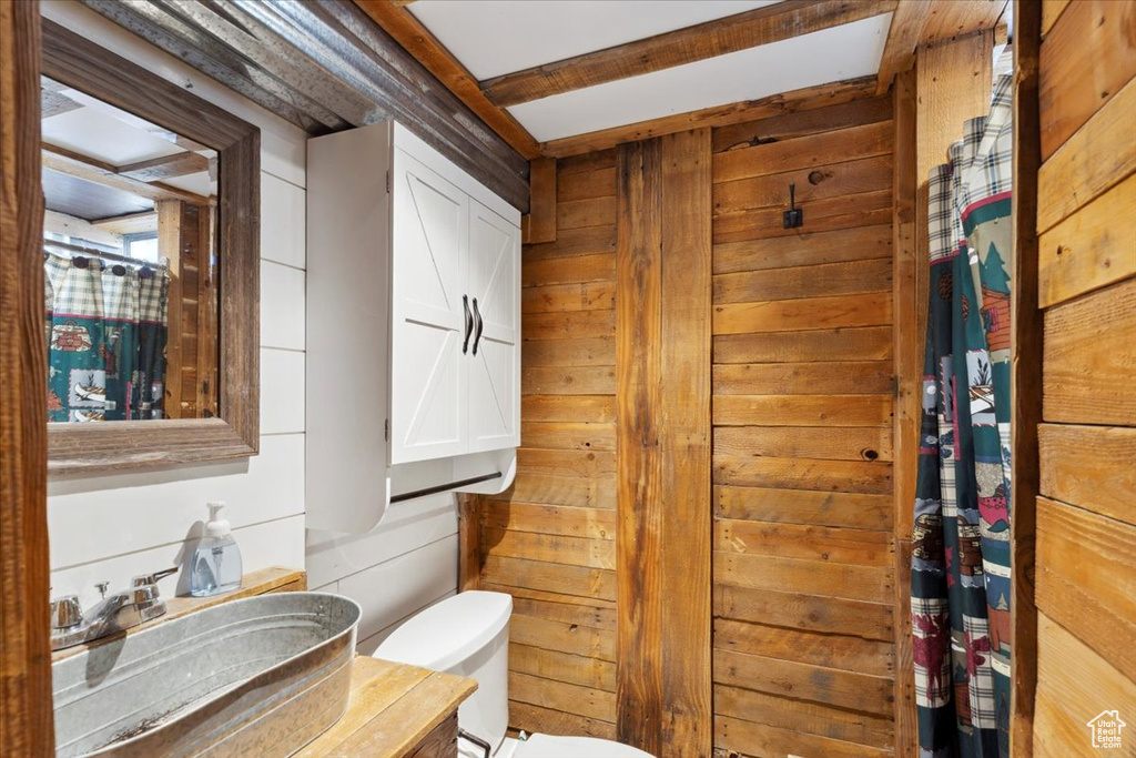 Bathroom with vanity, toilet, and wood walls