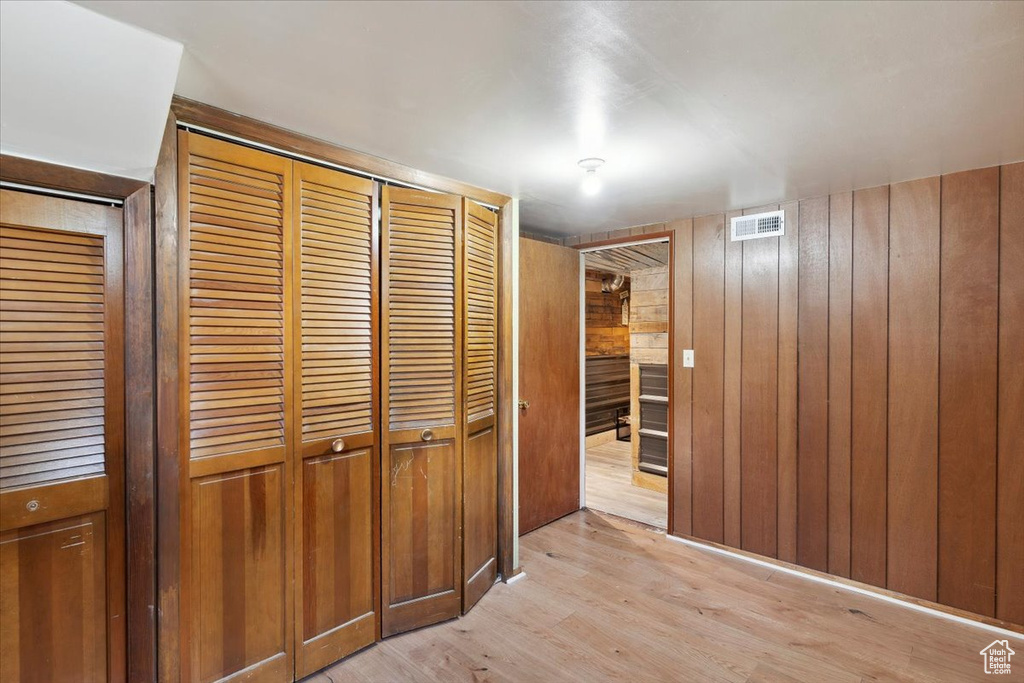 Hall featuring wood walls, light wood-style flooring, and visible vents