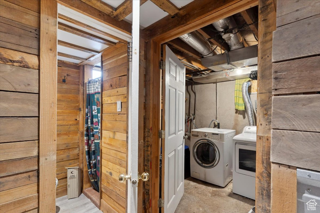 Washroom featuring wooden walls, separate washer and dryer, and laundry area