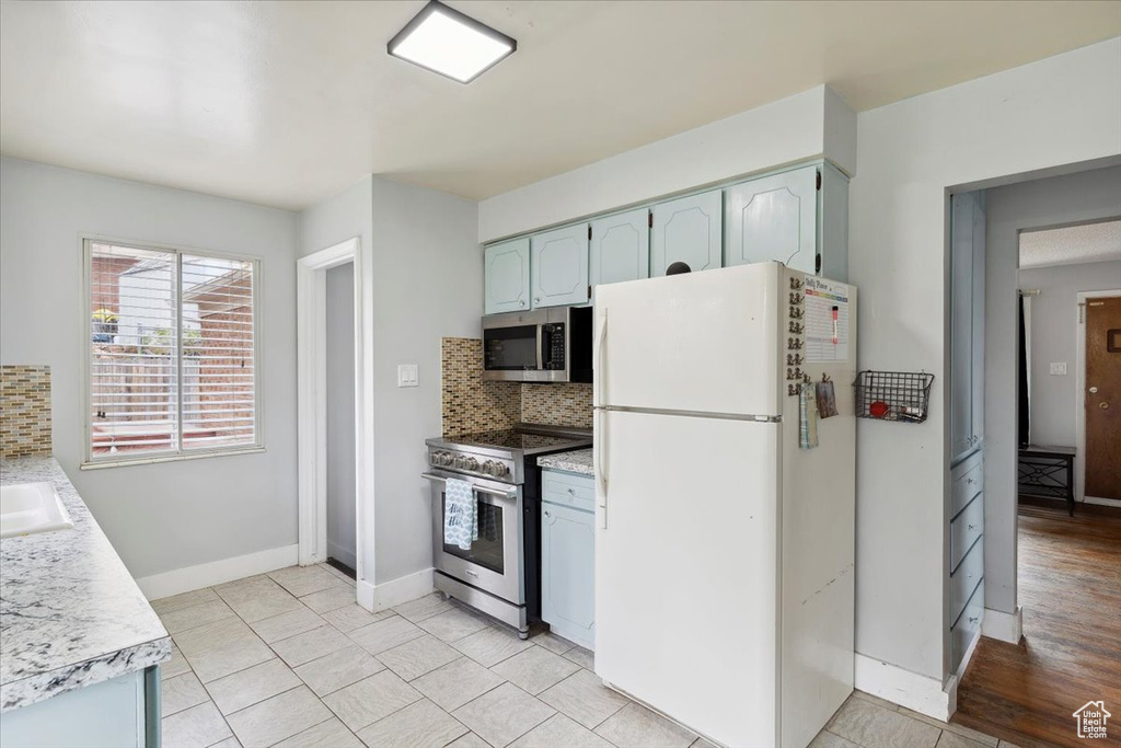 Kitchen with light countertops, decorative backsplash, and stainless steel appliances