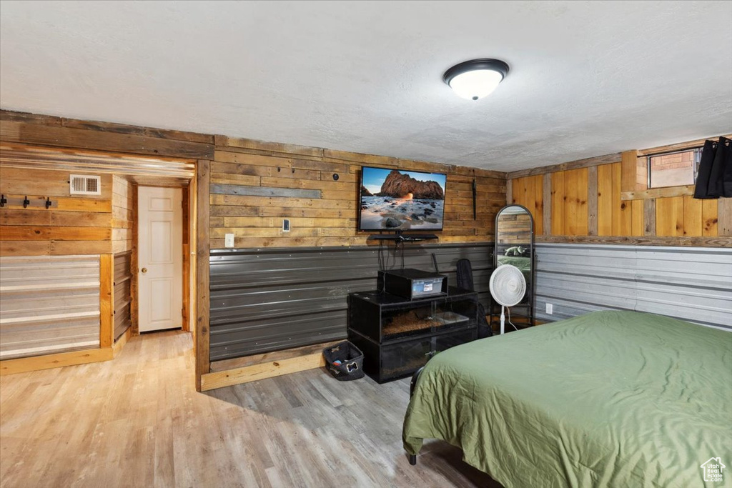 Bedroom featuring visible vents, wood walls, and wood finished floors