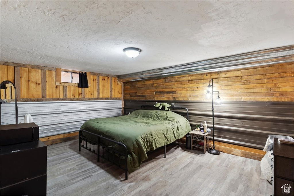 Bedroom featuring a textured ceiling, wood walls, and wood finished floors
