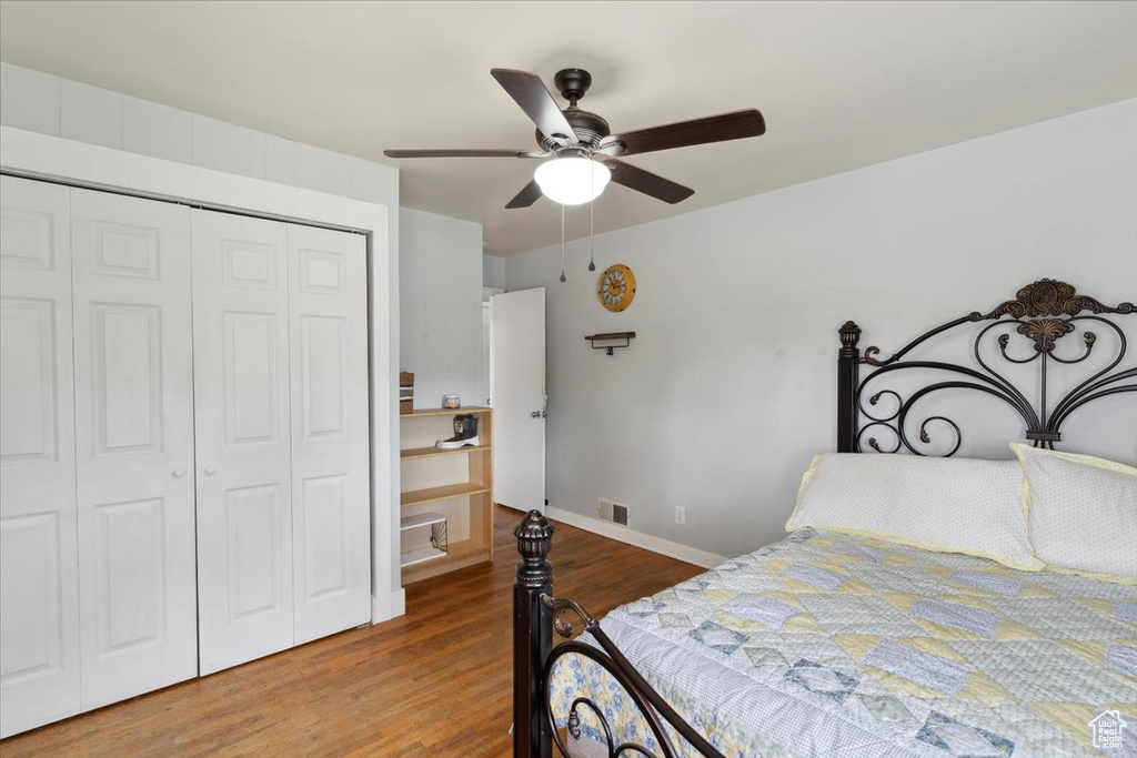 Bedroom featuring visible vents, a closet, wood finished floors, baseboards, and ceiling fan