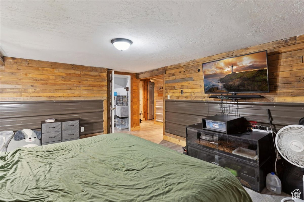 Bedroom featuring wood walls, a textured ceiling, and wood finished floors