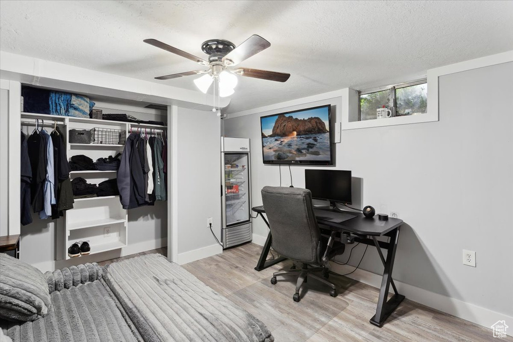 Office space with baseboards, a textured ceiling, ceiling fan, and light wood-style flooring