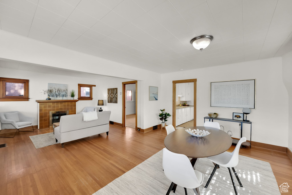 Dining room with a tiled fireplace, baseboards, and light wood finished floors