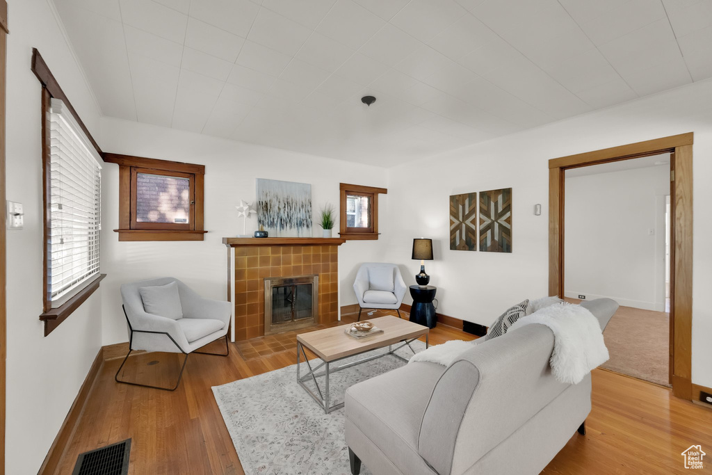 Living room with visible vents, baseboards, wood finished floors, and a tile fireplace