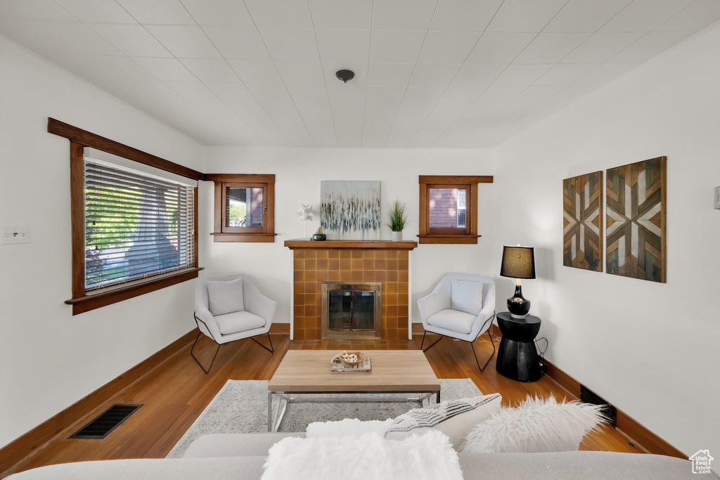 Living area with visible vents, baseboards, wood finished floors, and a tile fireplace