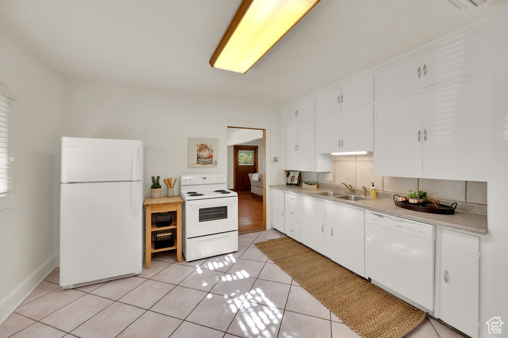 Kitchen with white appliances, white cabinets, a sink, and light countertops