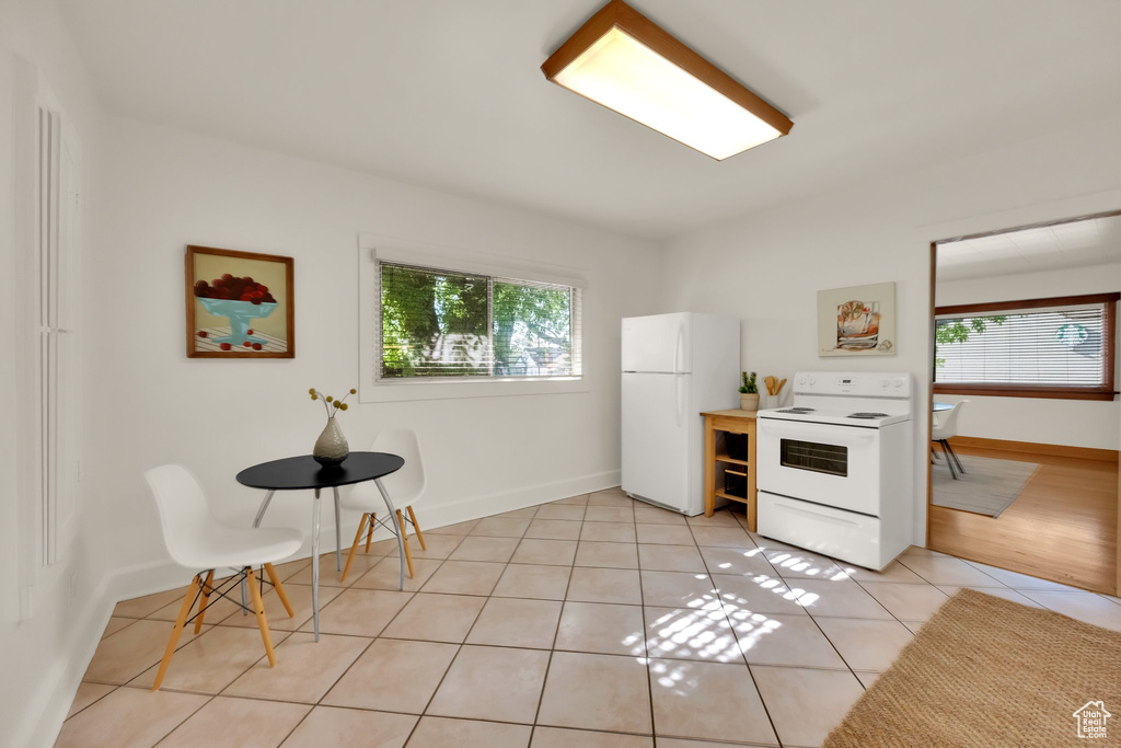 Kitchen featuring baseboards, light tile patterned flooring, and white appliances