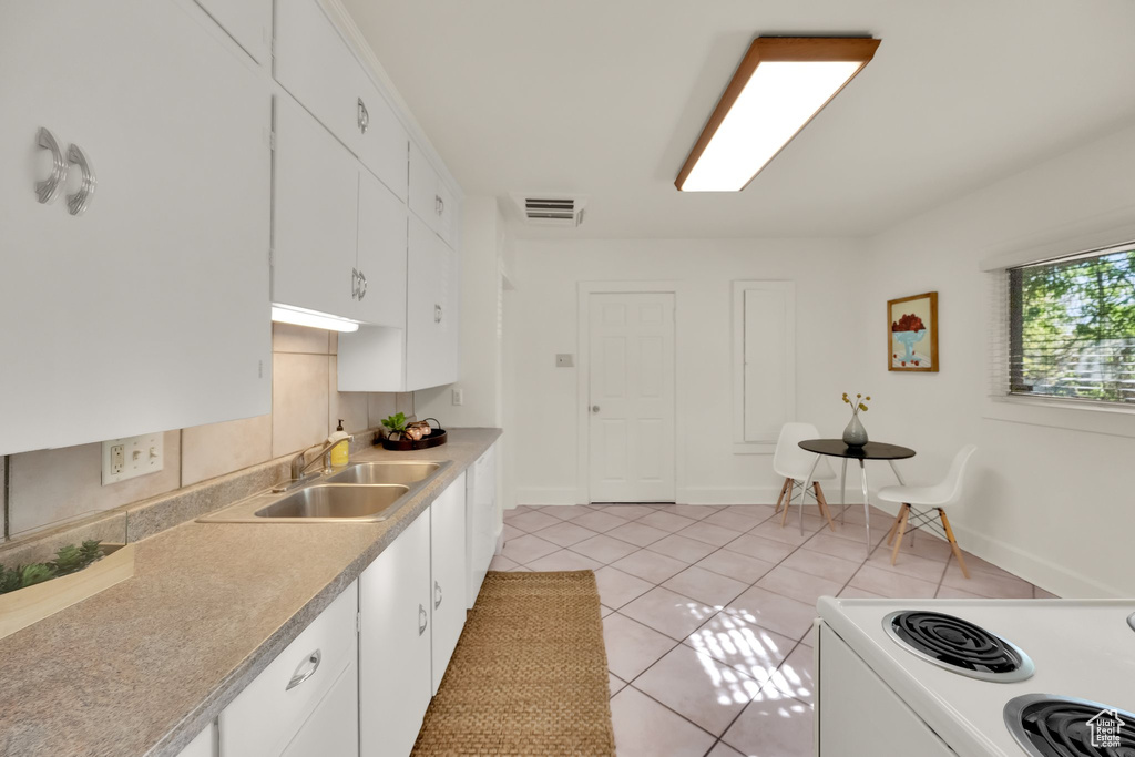 Kitchen with a sink, white cabinetry, light tile patterned floors, visible vents, and white electric stove