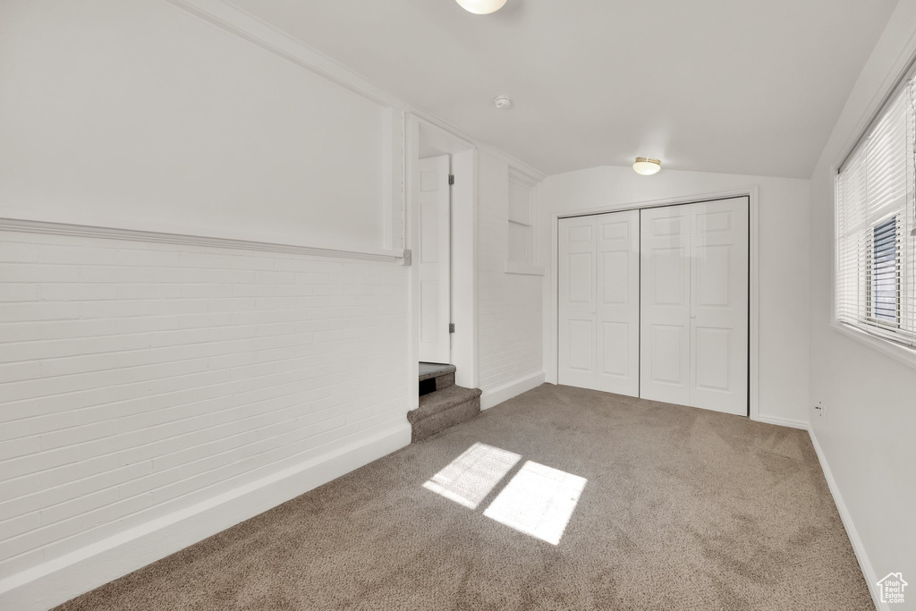 Unfurnished bedroom with carpet floors, baseboards, lofted ceiling, and a closet