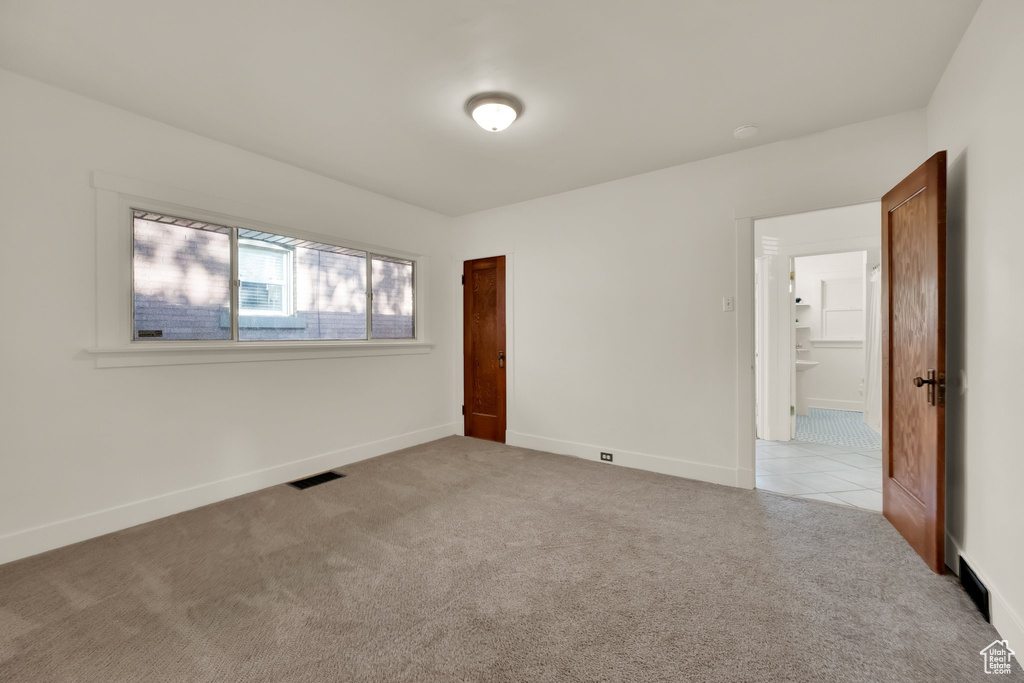 Unfurnished bedroom with visible vents, baseboards, and light colored carpet