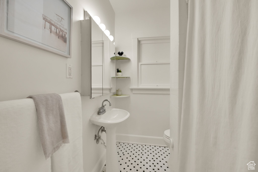 Full bathroom with baseboards, a shower with shower curtain, and toilet