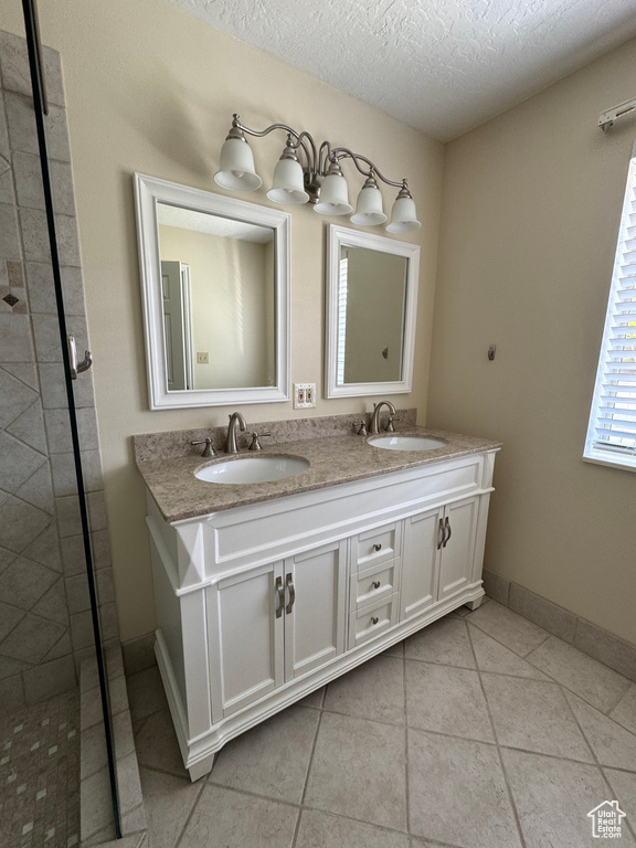 Full bathroom with double vanity, a textured ceiling, a sink, and tile patterned floors