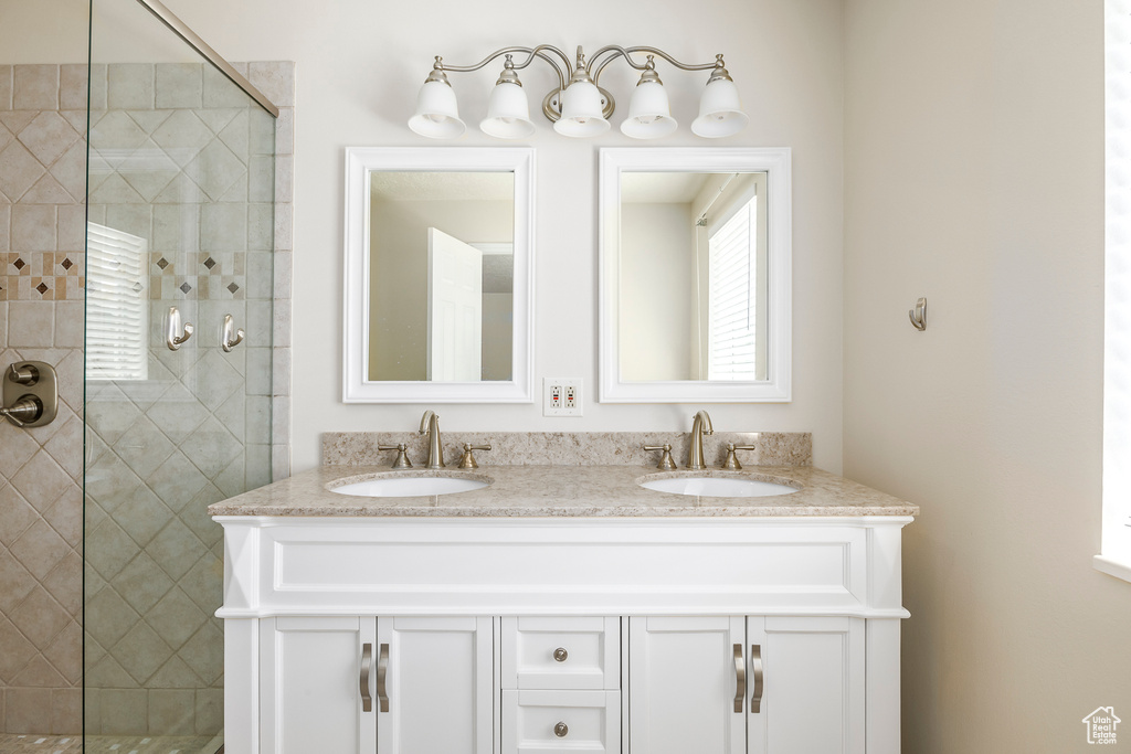 Full bathroom with double vanity, a tile shower, and a sink