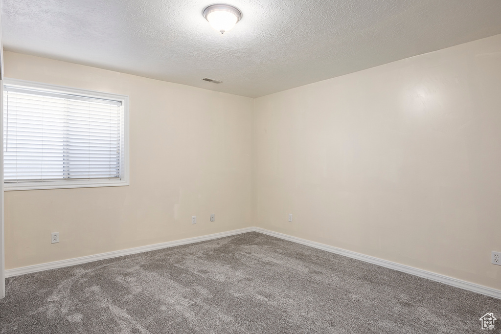 Spare room with visible vents, carpet flooring, a textured ceiling, and baseboards