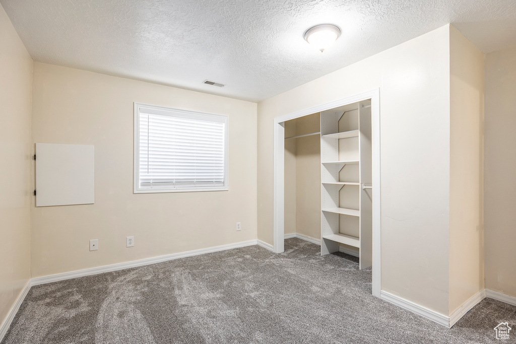 Unfurnished bedroom with carpet floors, visible vents, a closet, baseboards, and a textured ceiling