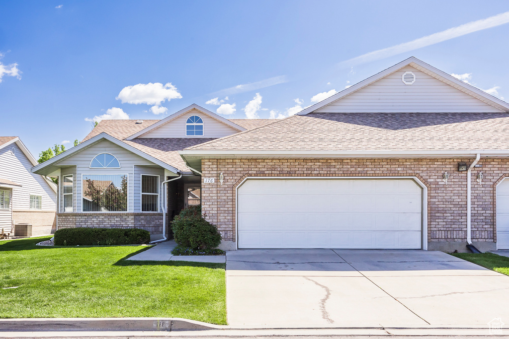 View of front of property featuring concrete driveway, central AC, a shingled roof, and a front lawn