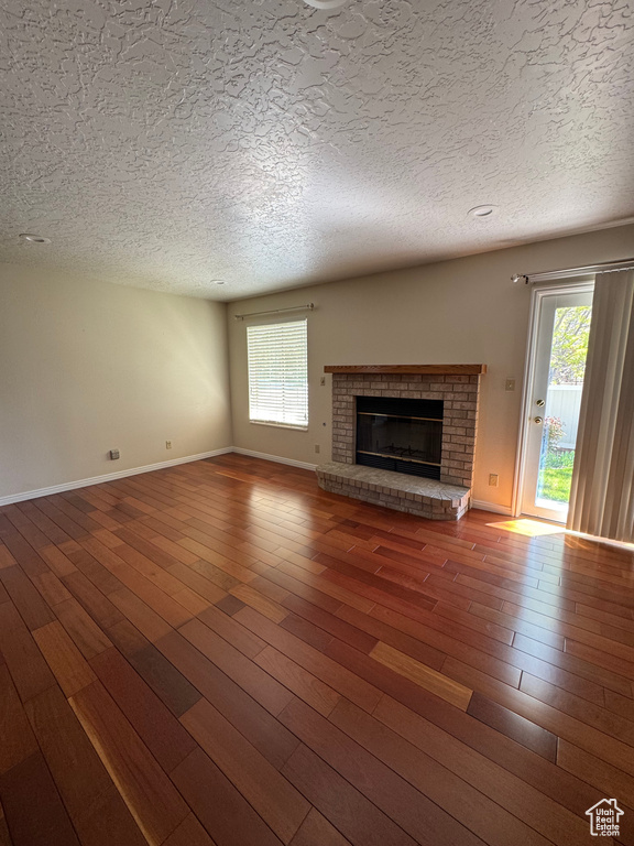 Unfurnished living room with wood-type flooring, a textured ceiling, and a fireplace