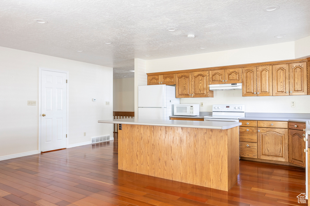 Kitchen with visible vents, white appliances, a center island, light countertops, and under cabinet range hood