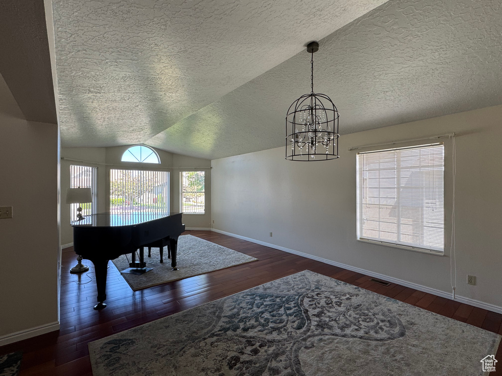 Dining area featuring an inviting chandelier, a textured ceiling, baseboards, and hardwood / wood-style floors