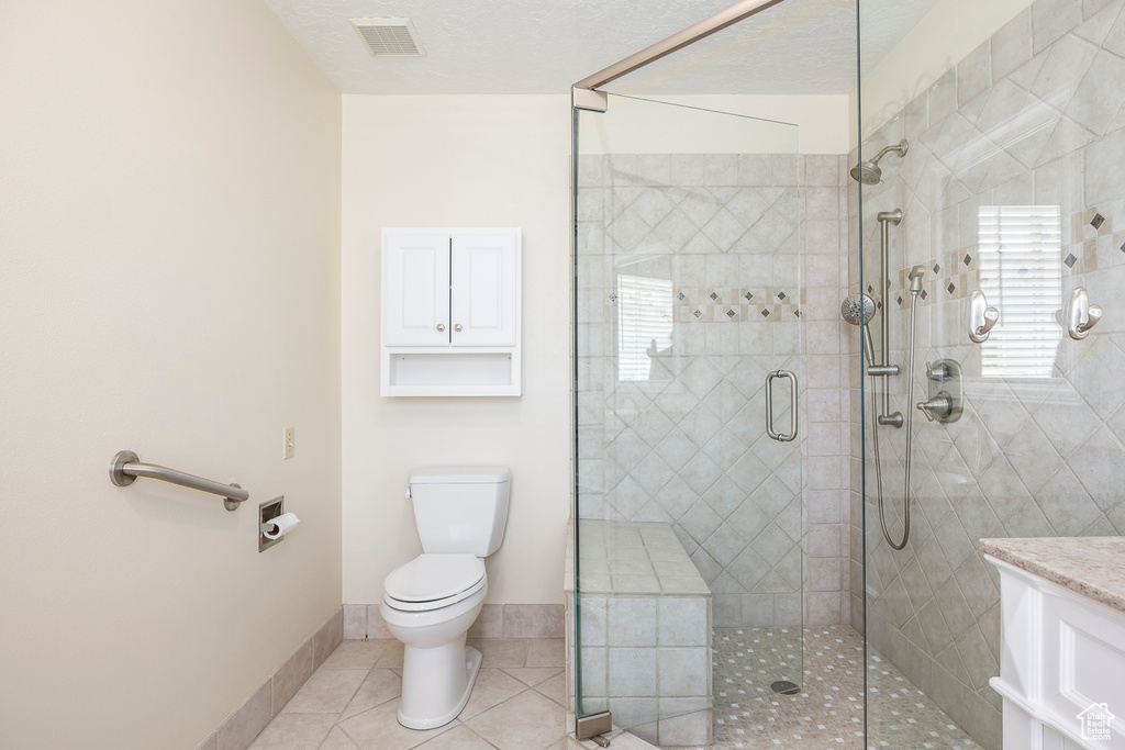 Full bath with a tile shower, toilet, tile patterned floors, baseboards, and visible vents