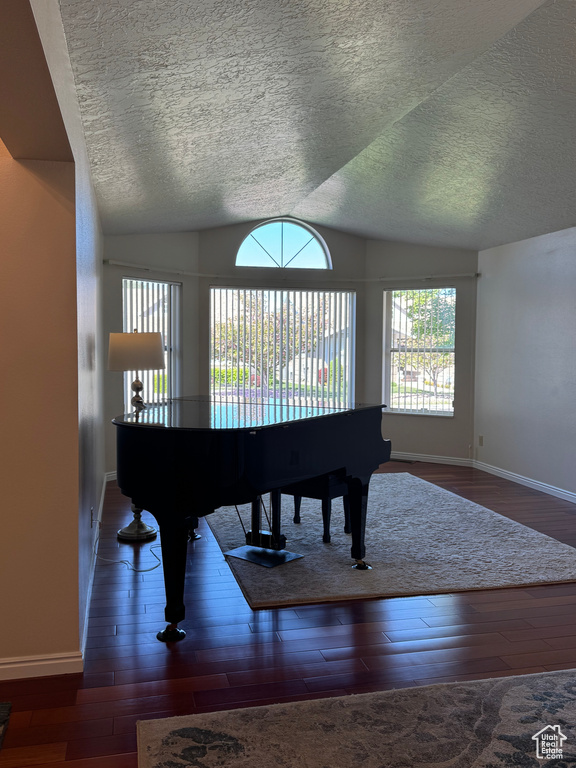 Sitting room with a textured ceiling, baseboards, vaulted ceiling, and wood finished floors