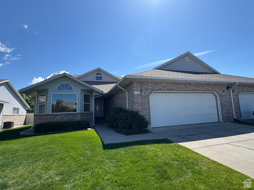 Single story home with an attached garage, a front yard, brick siding, and concrete driveway