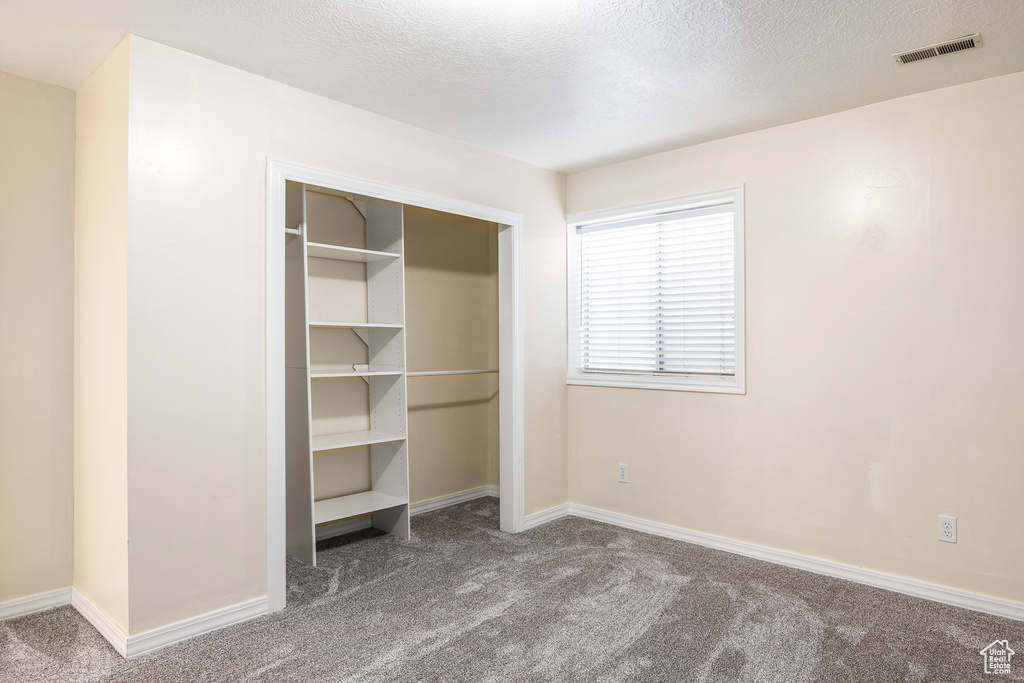 Unfurnished bedroom with visible vents, carpet flooring, baseboards, and a closet