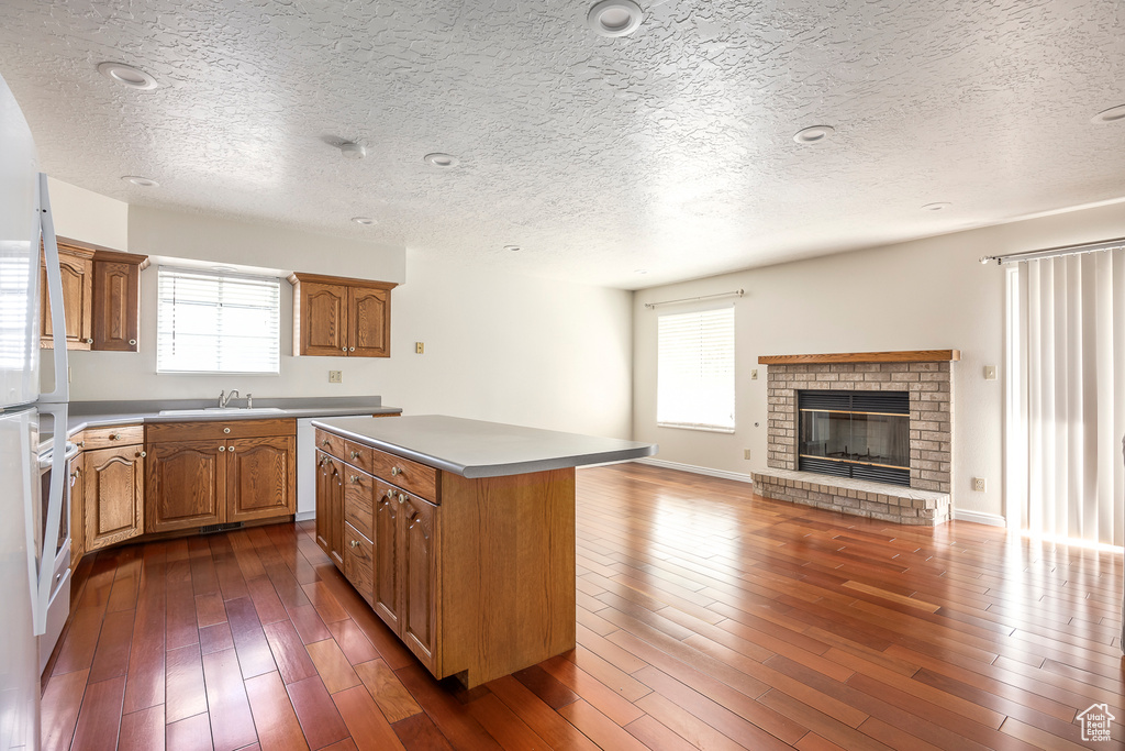 Kitchen with a center island, a sink, a textured ceiling, and plenty of natural light