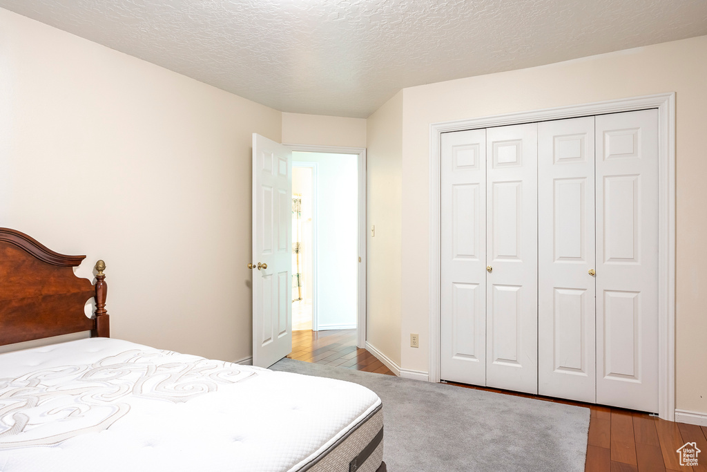 Bedroom with a closet, baseboards, a textured ceiling, and wood finished floors