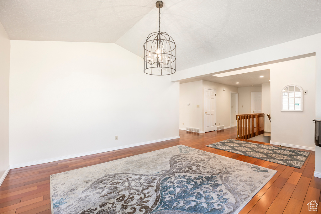 Dining space featuring visible vents, vaulted ceiling, baseboards, a chandelier, and hardwood / wood-style floors