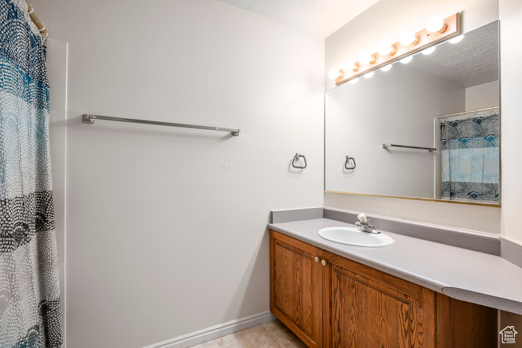 Bathroom featuring a shower with curtain, baseboards, and vanity