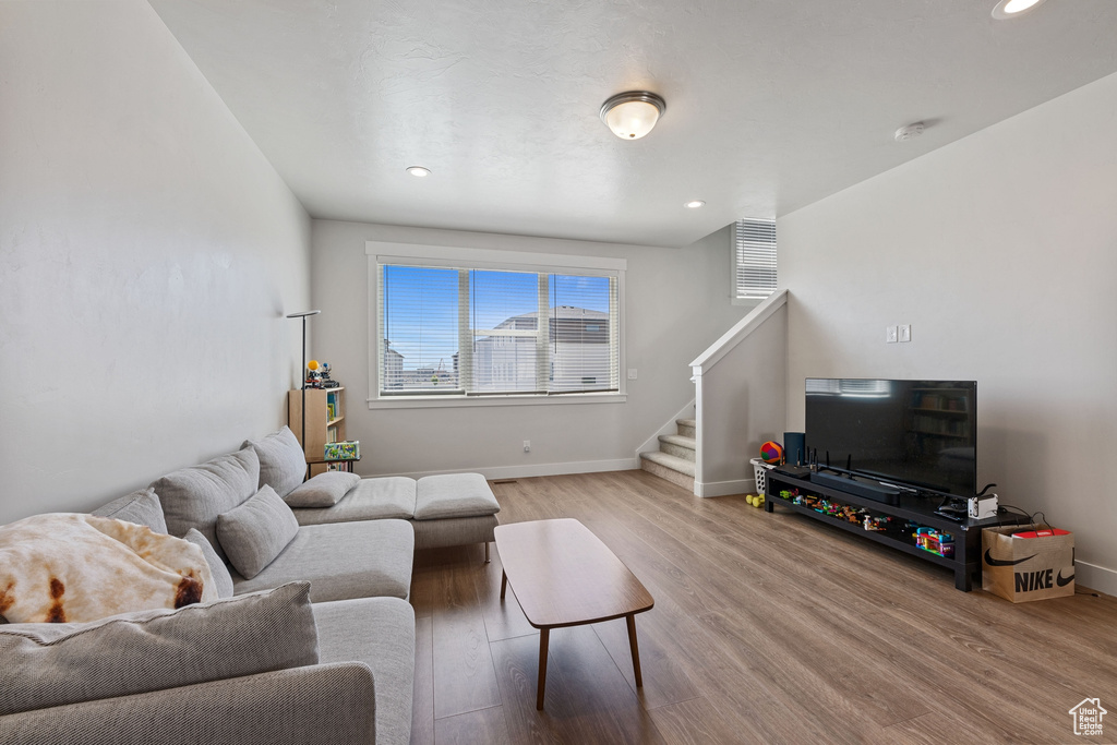 Living area featuring baseboards, recessed lighting, stairs, and wood finished floors