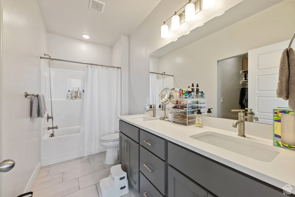Bathroom featuring a sink, toilet, double vanity, and visible vents