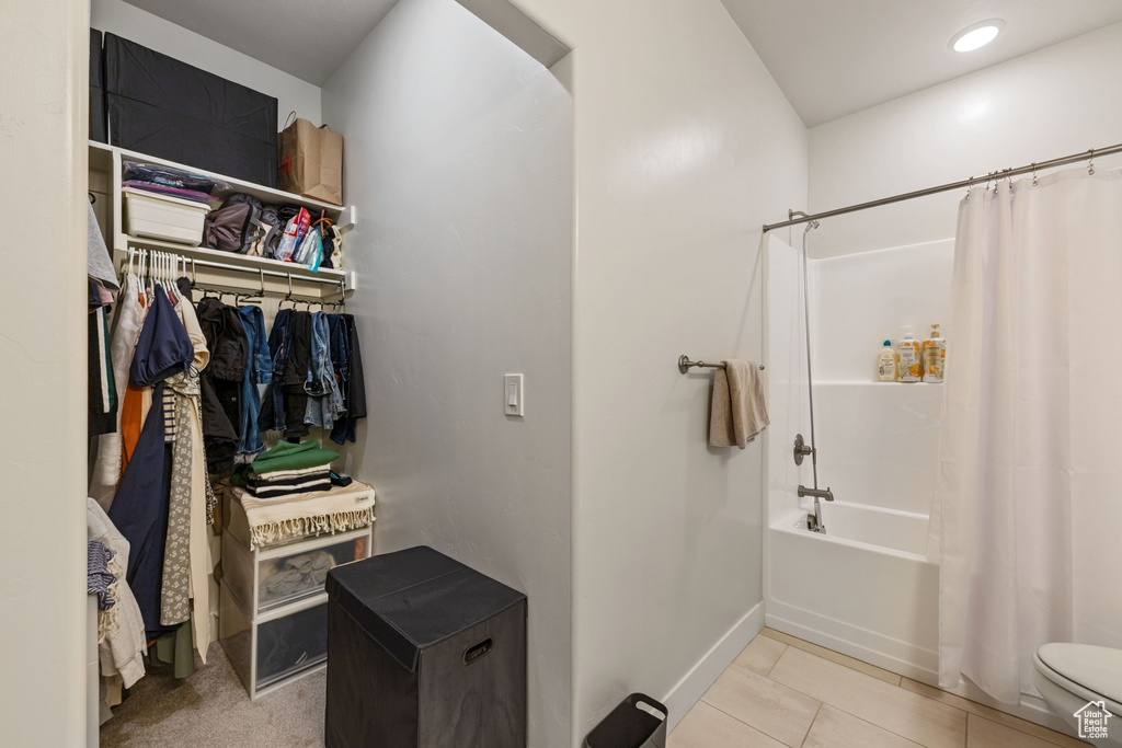 Bathroom with a walk in closet, tile patterned flooring, baseboards, toilet, and shower / tub combo with curtain