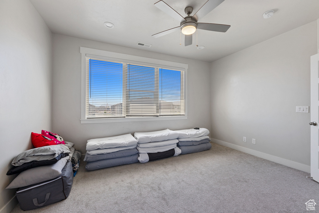 Living area with carpet flooring, baseboards, visible vents, and ceiling fan