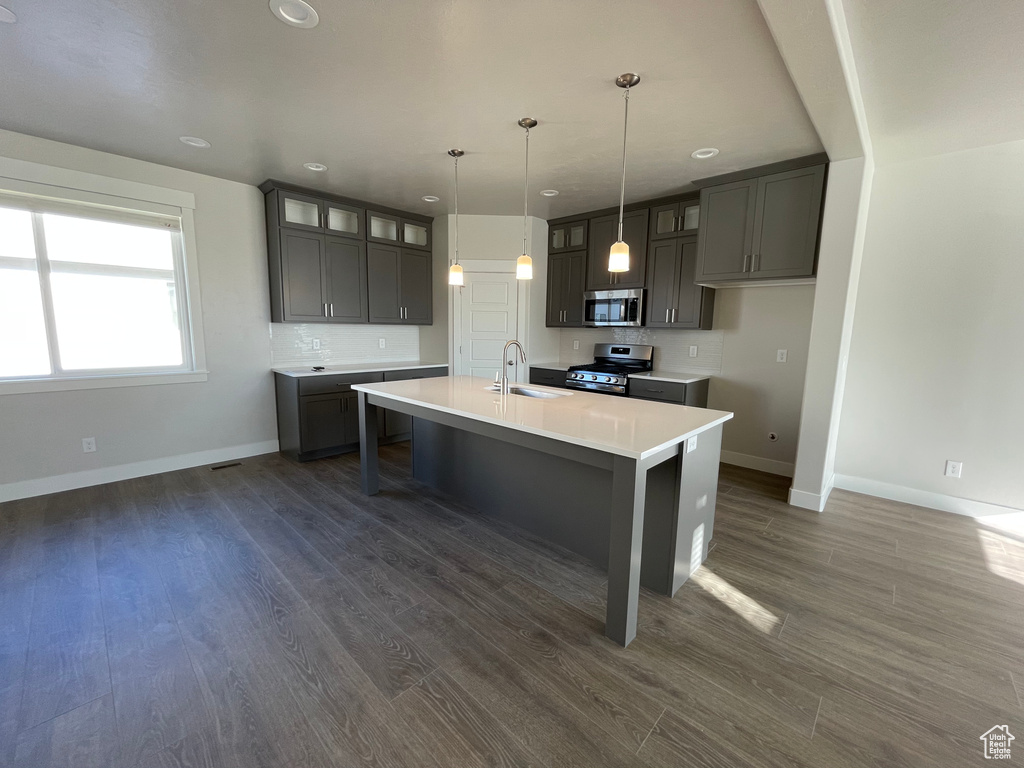 Kitchen with stainless steel appliances, a sink, baseboards, glass insert cabinets, and recessed lighting