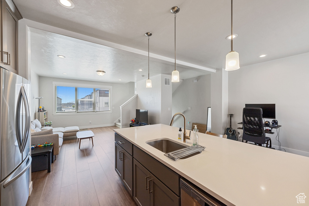 Kitchen with dark wood-style flooring, a sink, light countertops, stainless steel appliances, and open floor plan