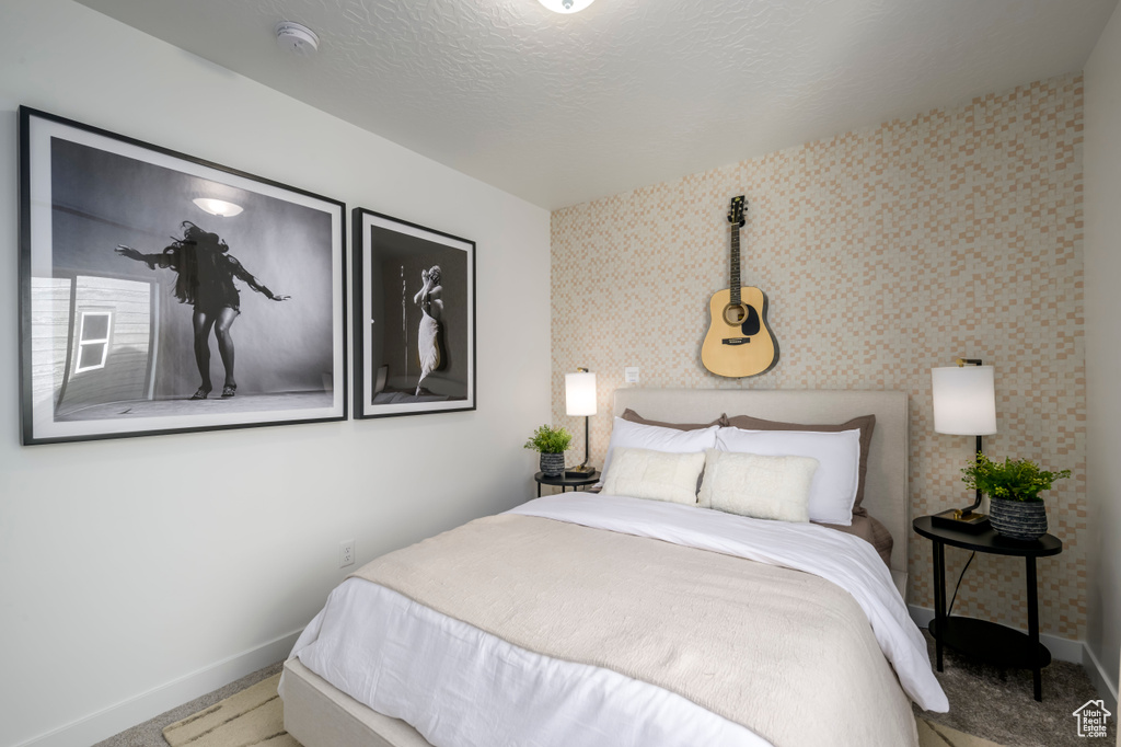 Carpeted bedroom featuring baseboards and wallpapered walls