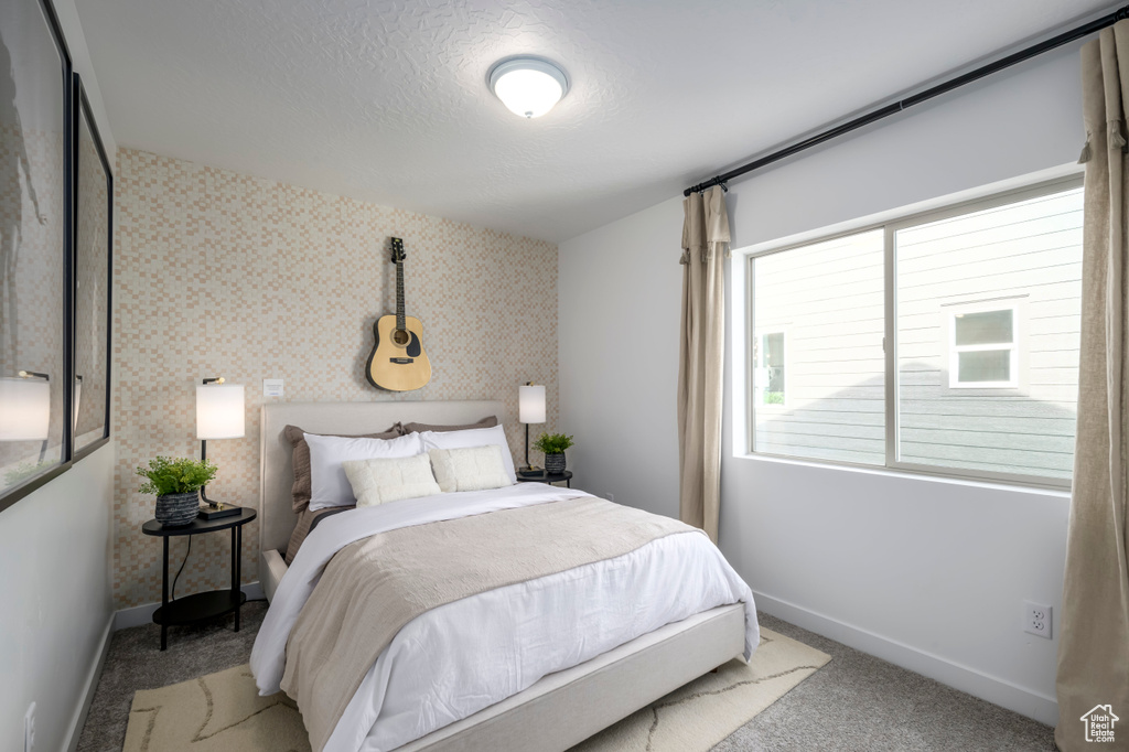 Carpeted bedroom featuring baseboards and wallpapered walls