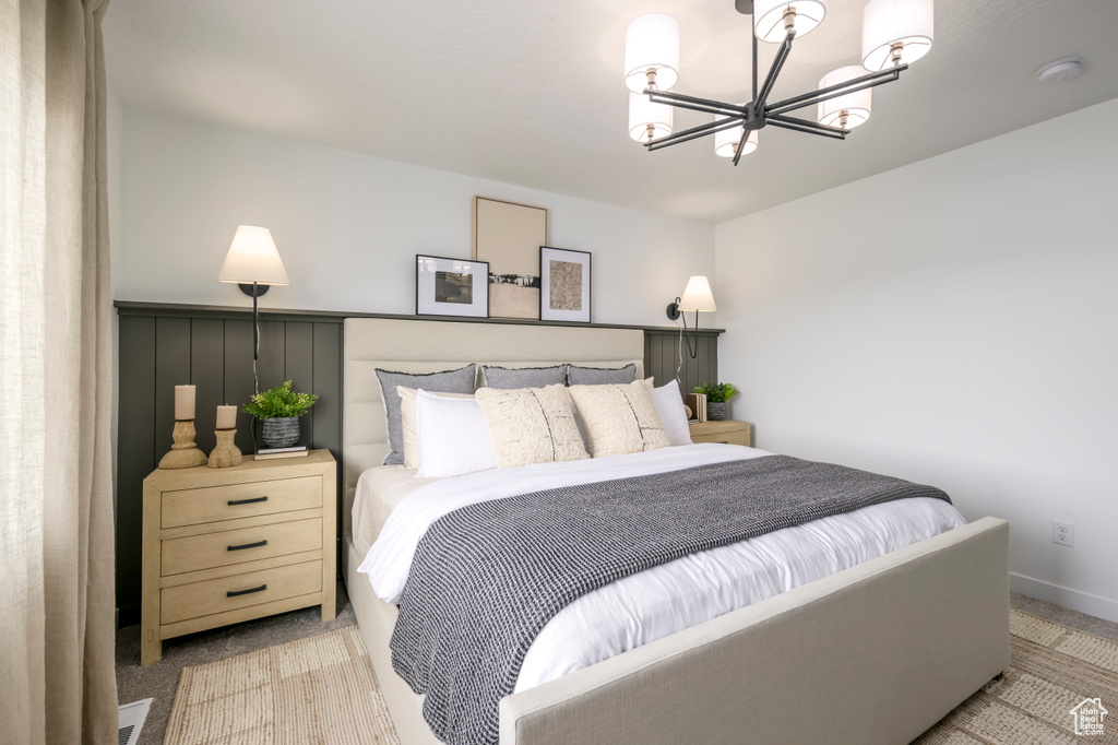 Bedroom featuring light colored carpet, baseboards, and a chandelier