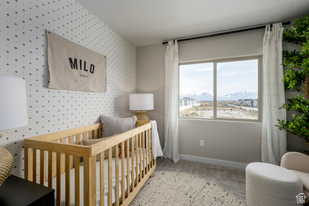 Carpeted bedroom featuring baseboards, a nursery area, a mountain view, and wallpapered walls