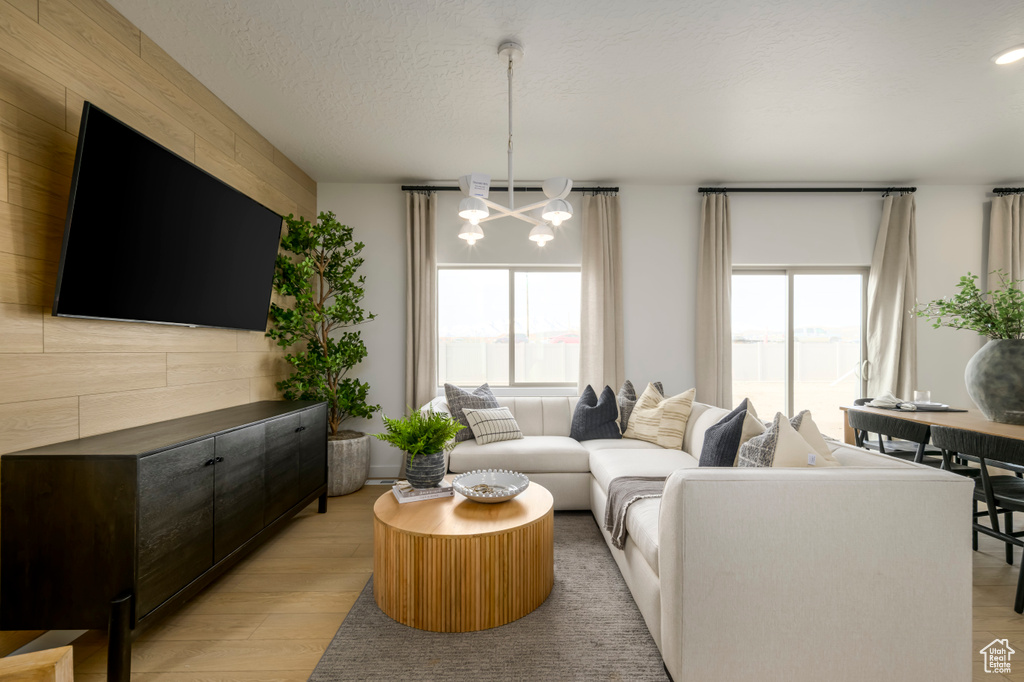Living area with a textured ceiling, an inviting chandelier, a wealth of natural light, and light wood finished floors