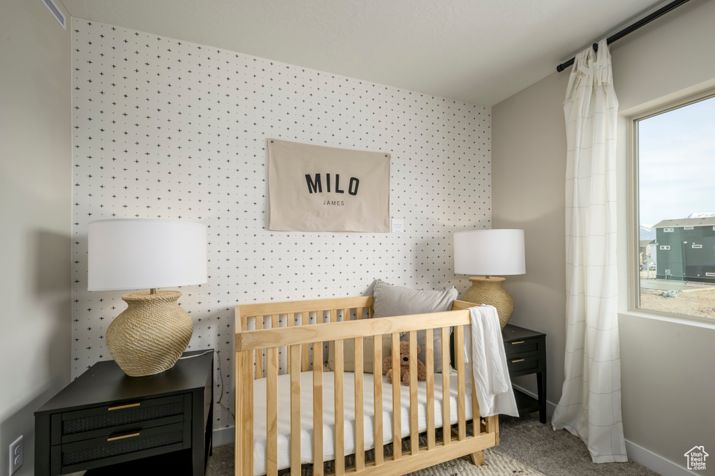 Bedroom featuring a nursery area, baseboards, and carpet
