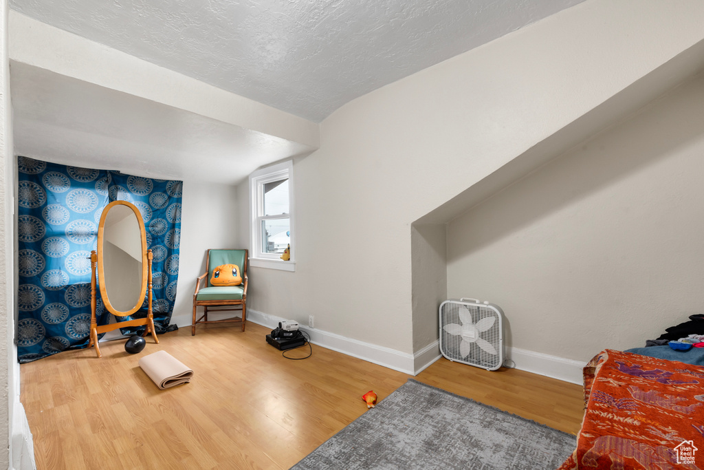 Sitting room featuring a textured ceiling, baseboards, and wood finished floors