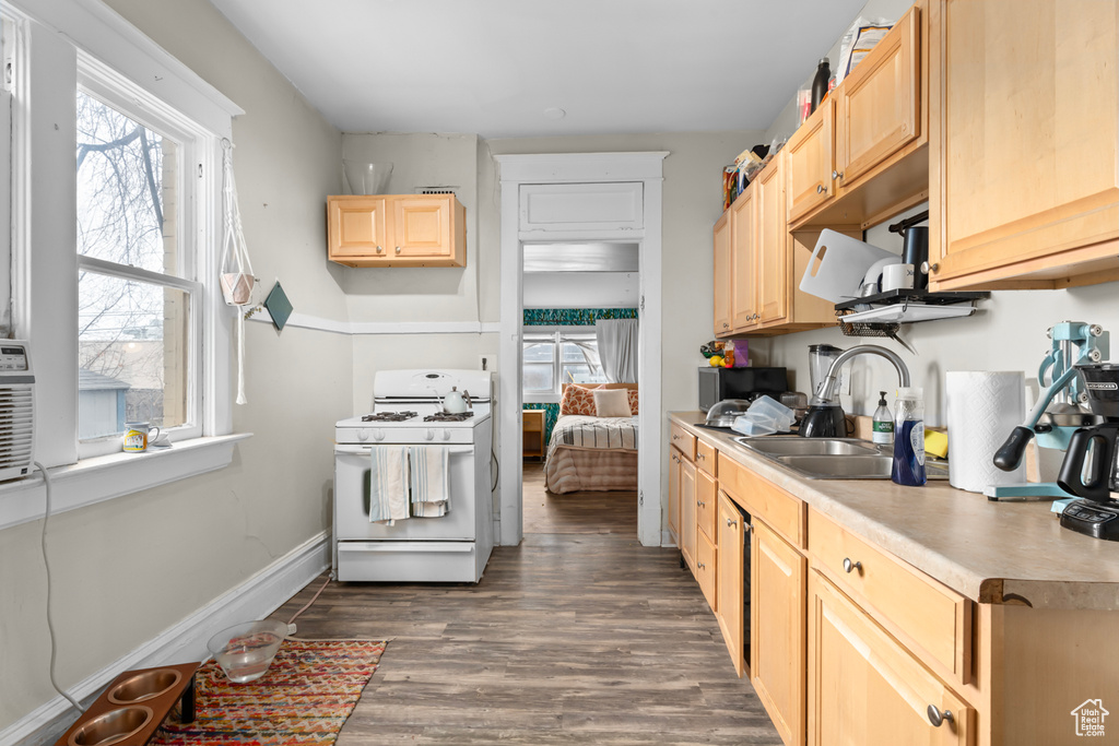 Kitchen featuring a sink, light brown cabinets, white range with gas stovetop, and dark wood-style flooring