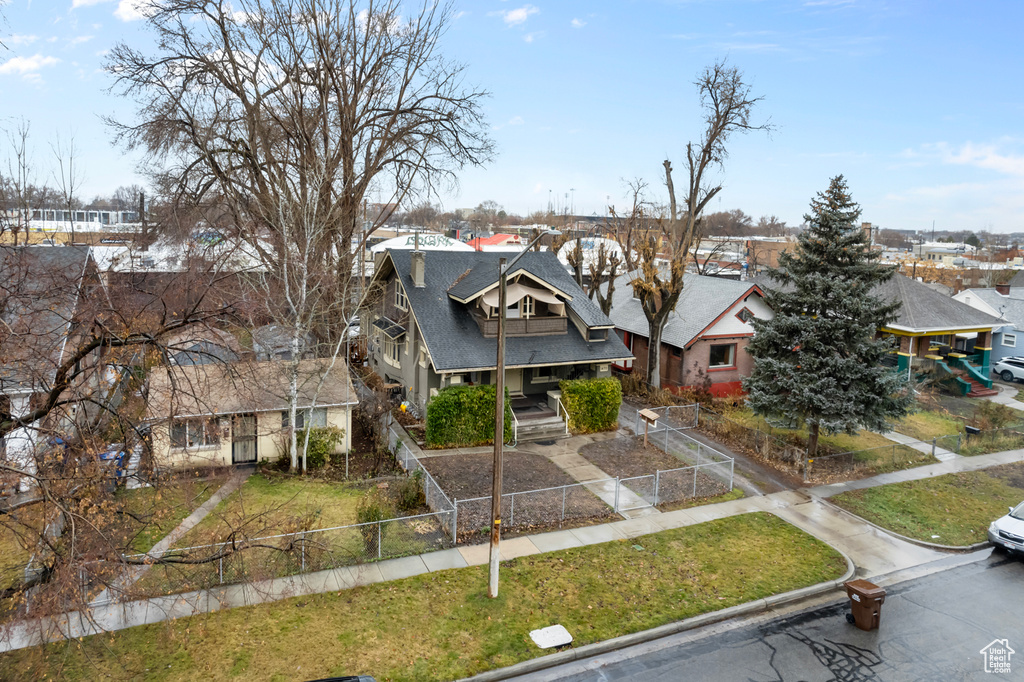 View of front of house with a shingled roof, fence, a front yard, and a residential view