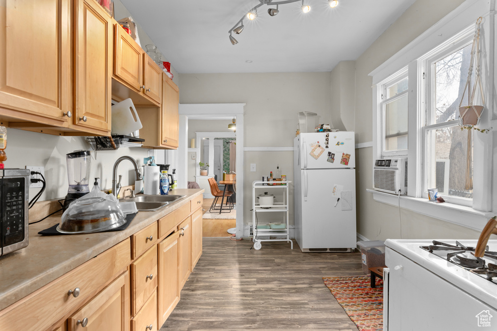 Kitchen featuring dark wood-style flooring, a sink, light countertops, light brown cabinets, and white appliances